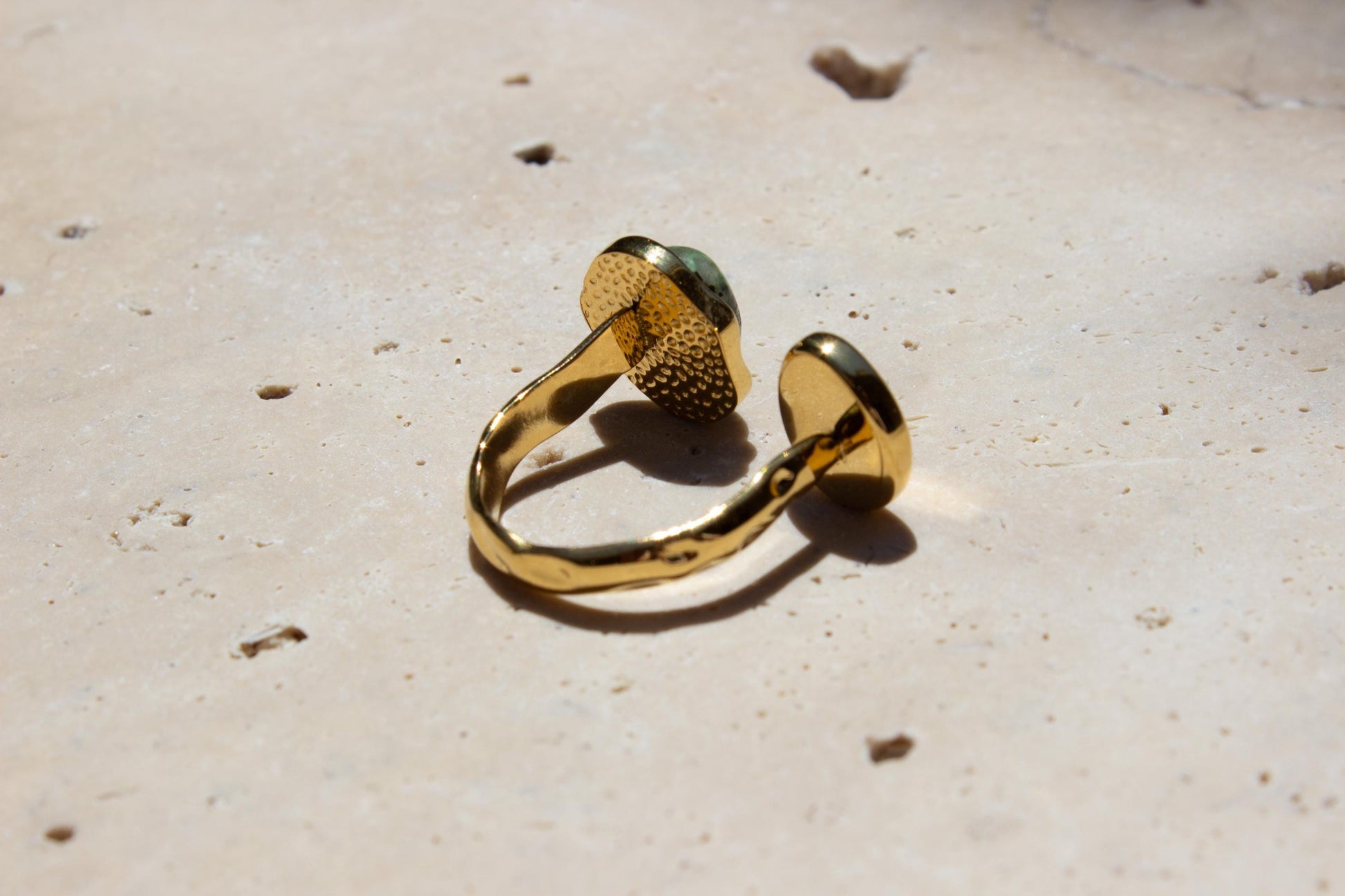 back side of a gold adjustable ring on a concrete tile.