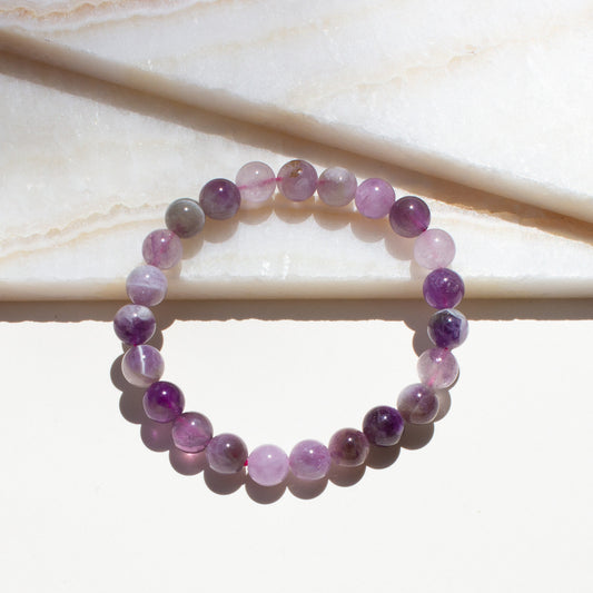 Round beaded bracelet with purple and pink amethyst stones on a light background.