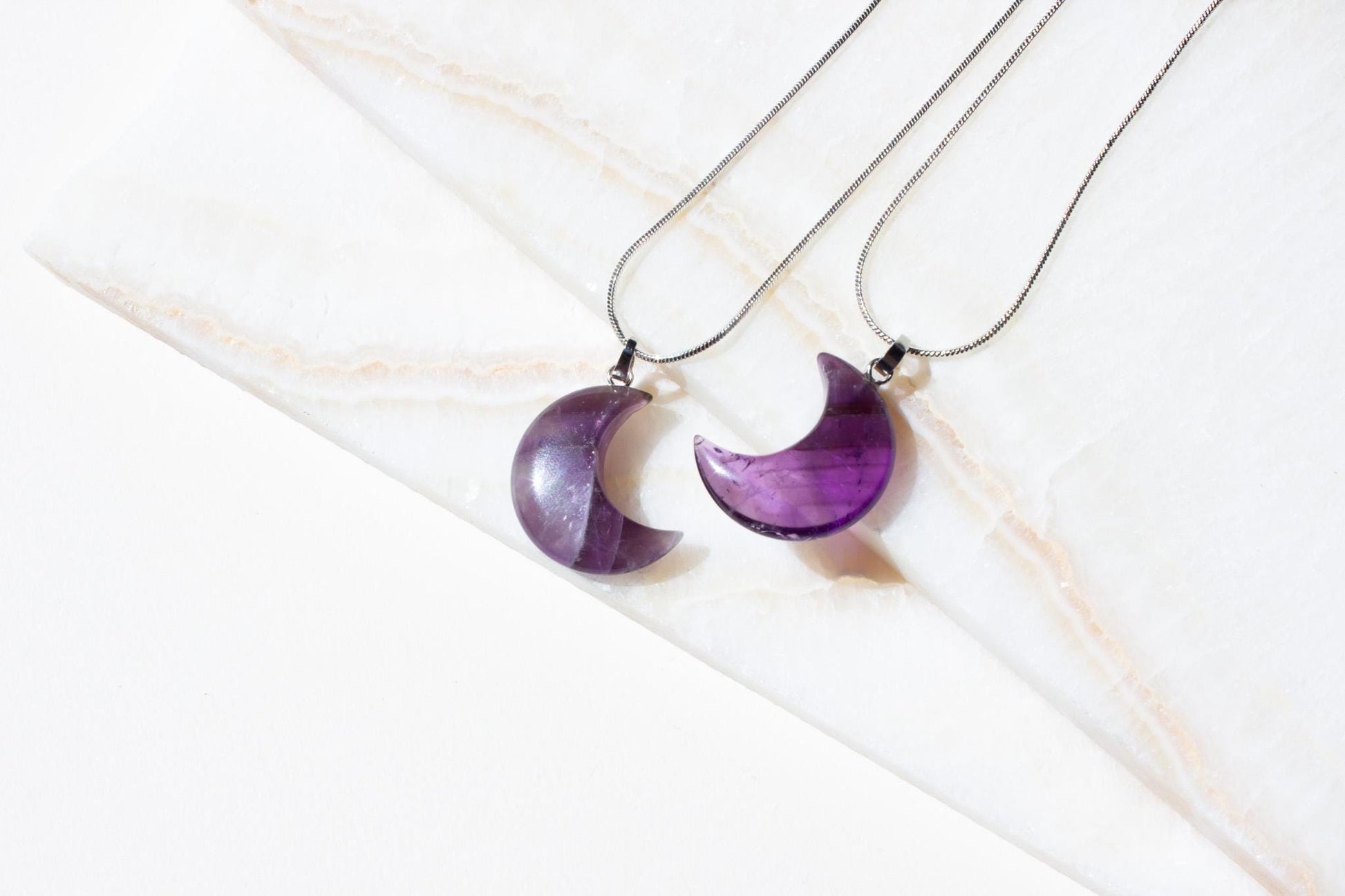 a pair of moon shaped pendants in amethyst crystal gemstone.