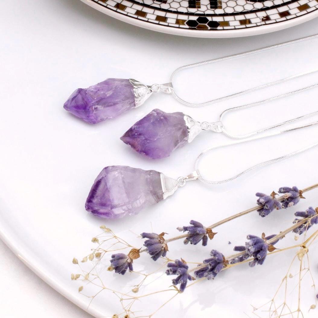 Purple crystal pendants next to lavender leaves.