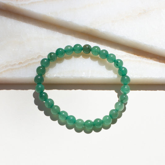 Green aventurine beaded bracelet on a light background.