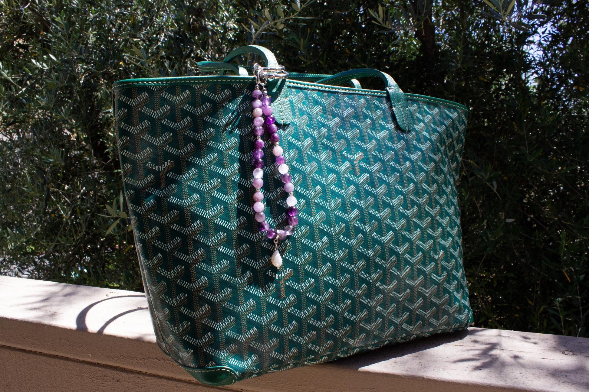 bag charm on a goyard green tote bag.