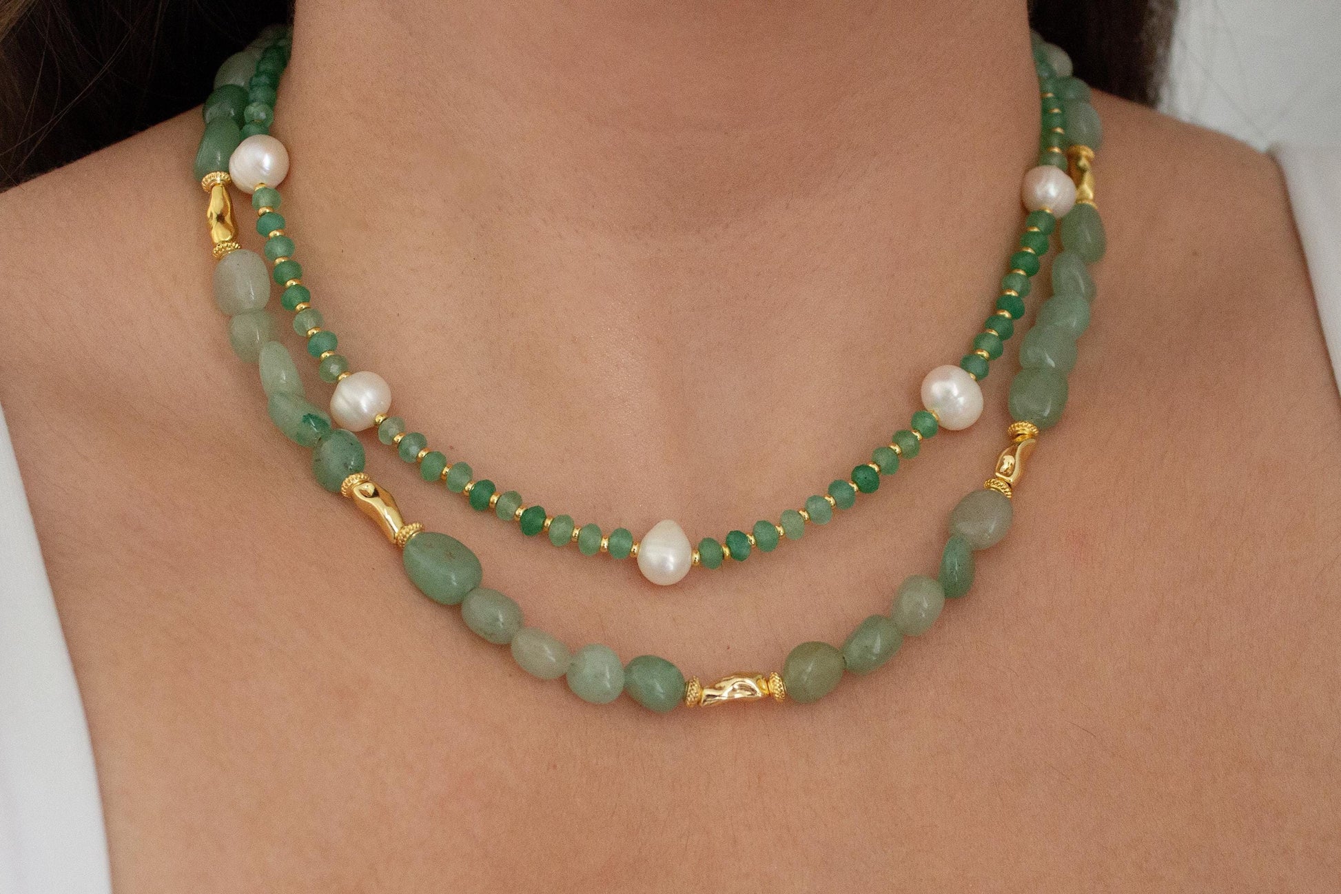girl wearing two green crystal necklaces stacked.
