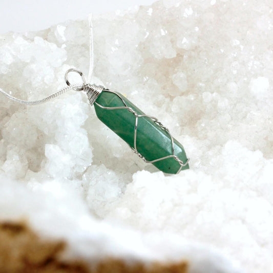 green aventurine crystal necklace laying on a clear quartz crystal.
