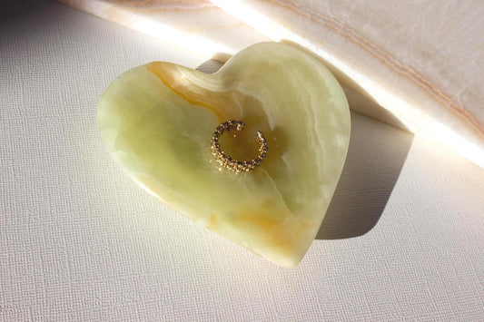 green onyx heart dish holding a gold ring.