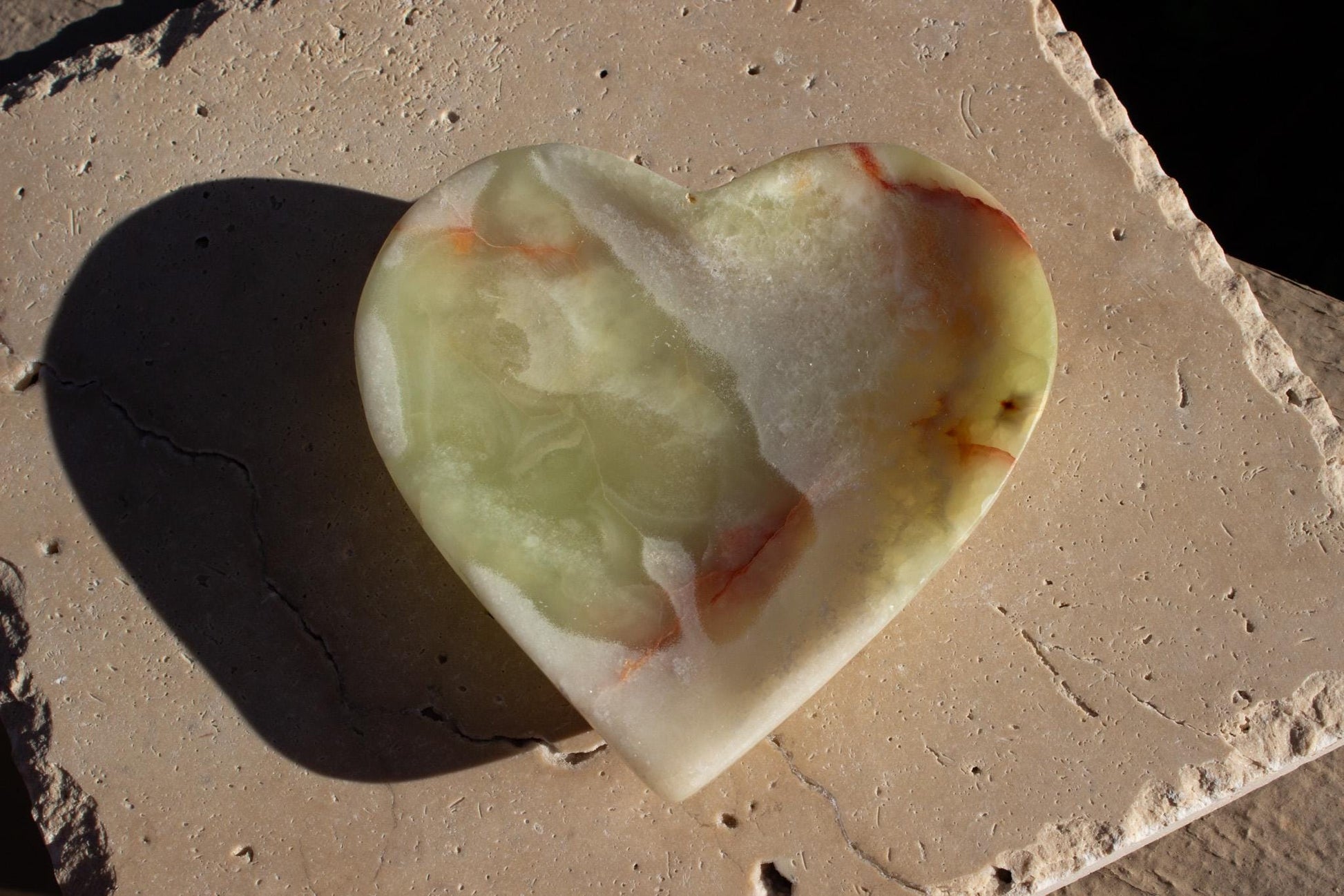 green onyx dish with red bands sitting on a beige tile.