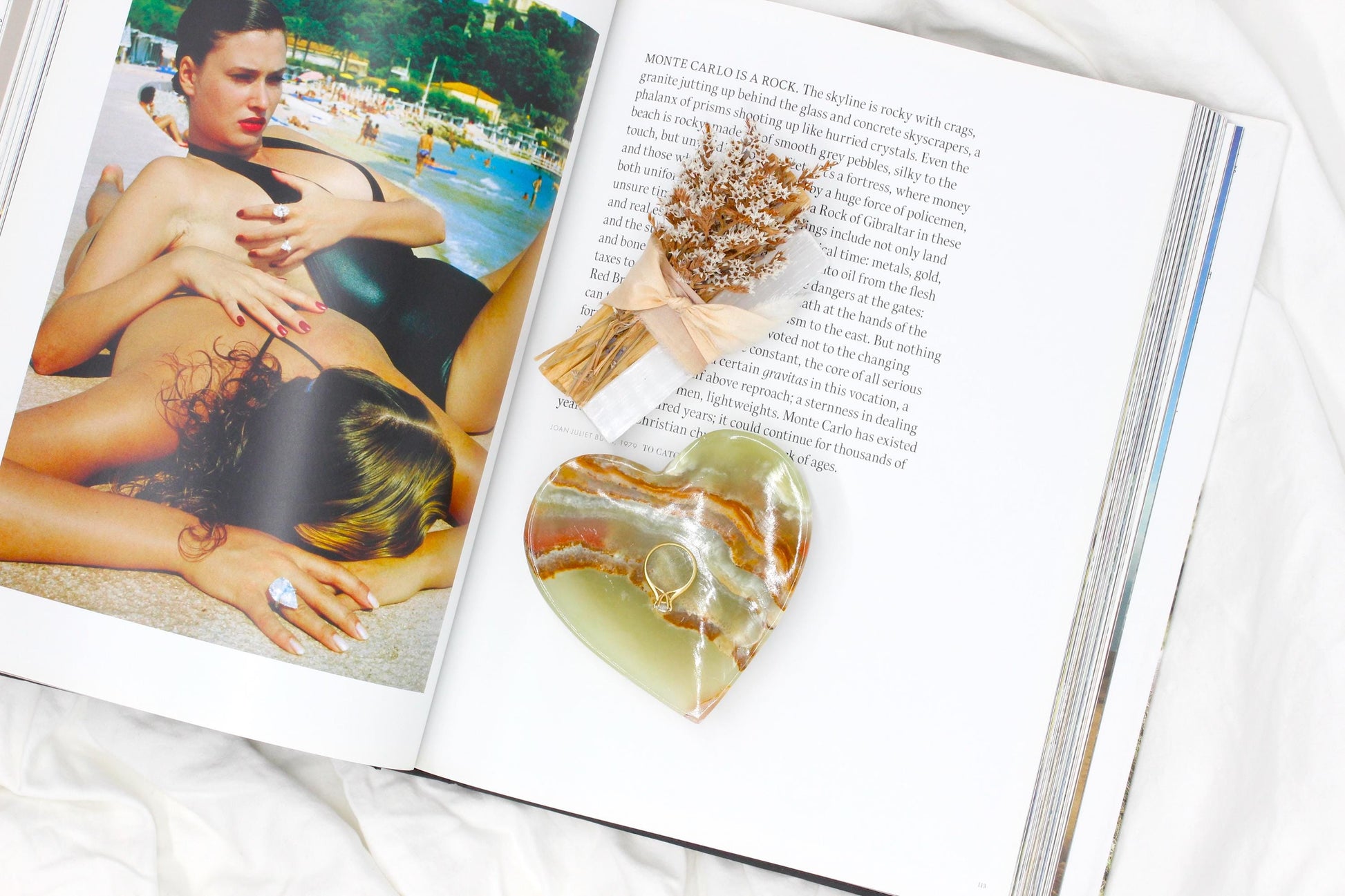 one green onyx dish with banding laying on a vogue fashion book. The green bowl is holding one engagement ring.
