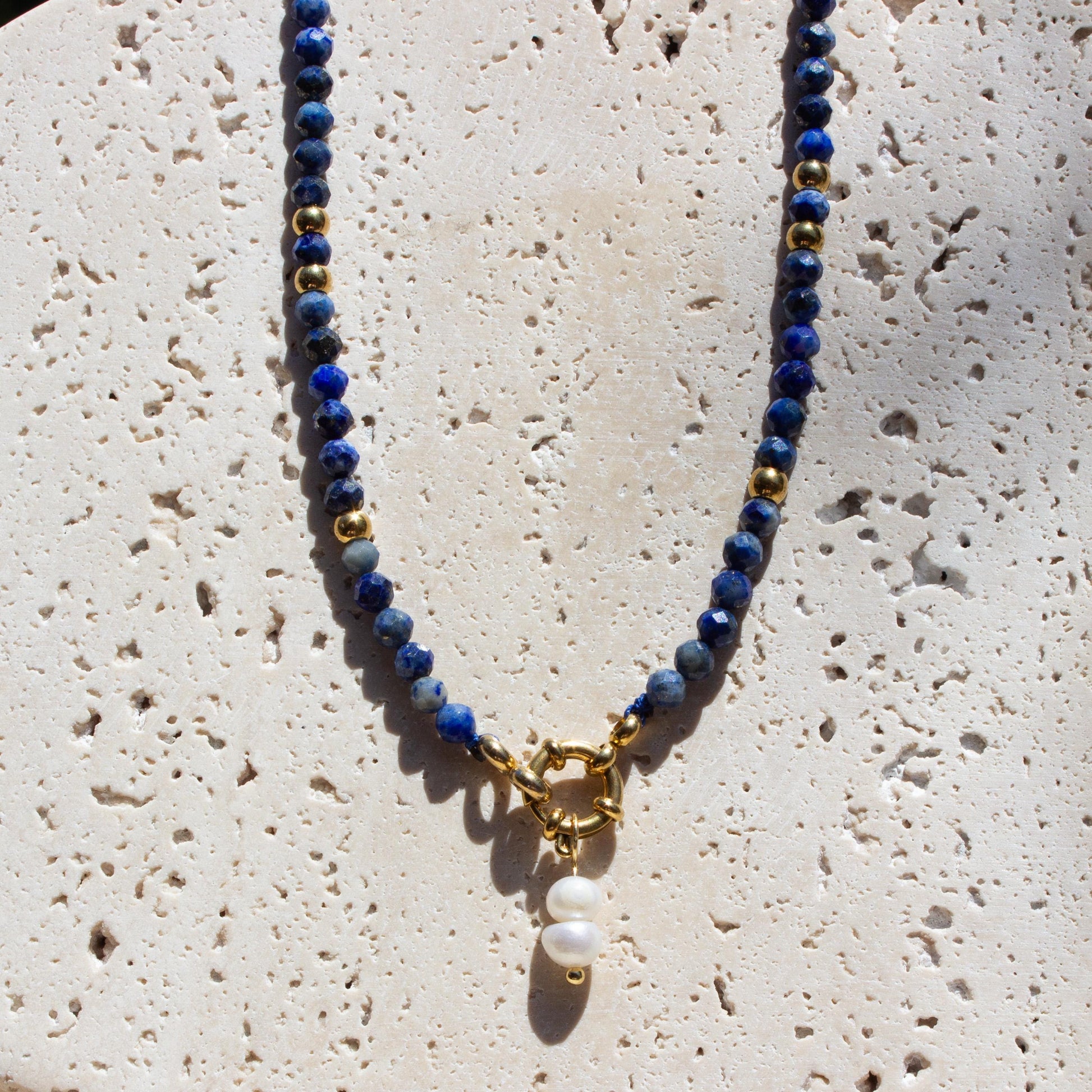lapis lazuli crystal necklace with gold accents and pearl charm.
