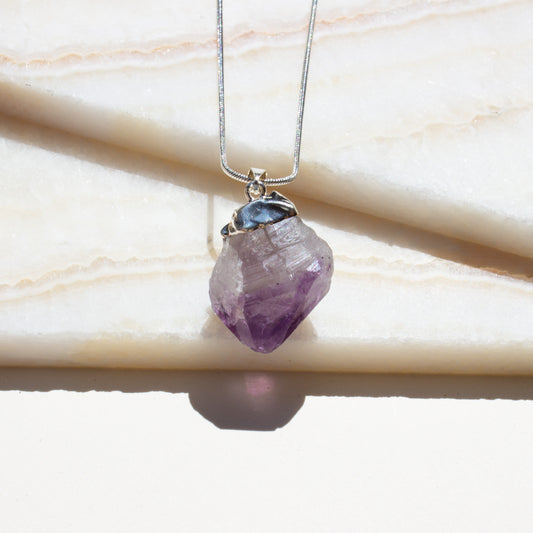 Necklace with a purple crystal pendant on a light background