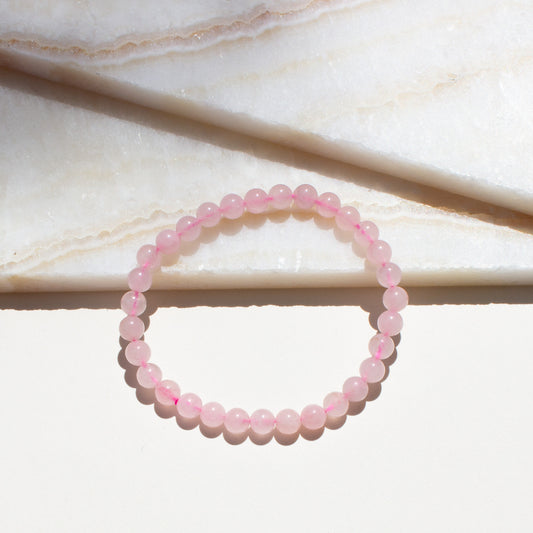 Pink rose quartz beaded bracelet on a marble surface.