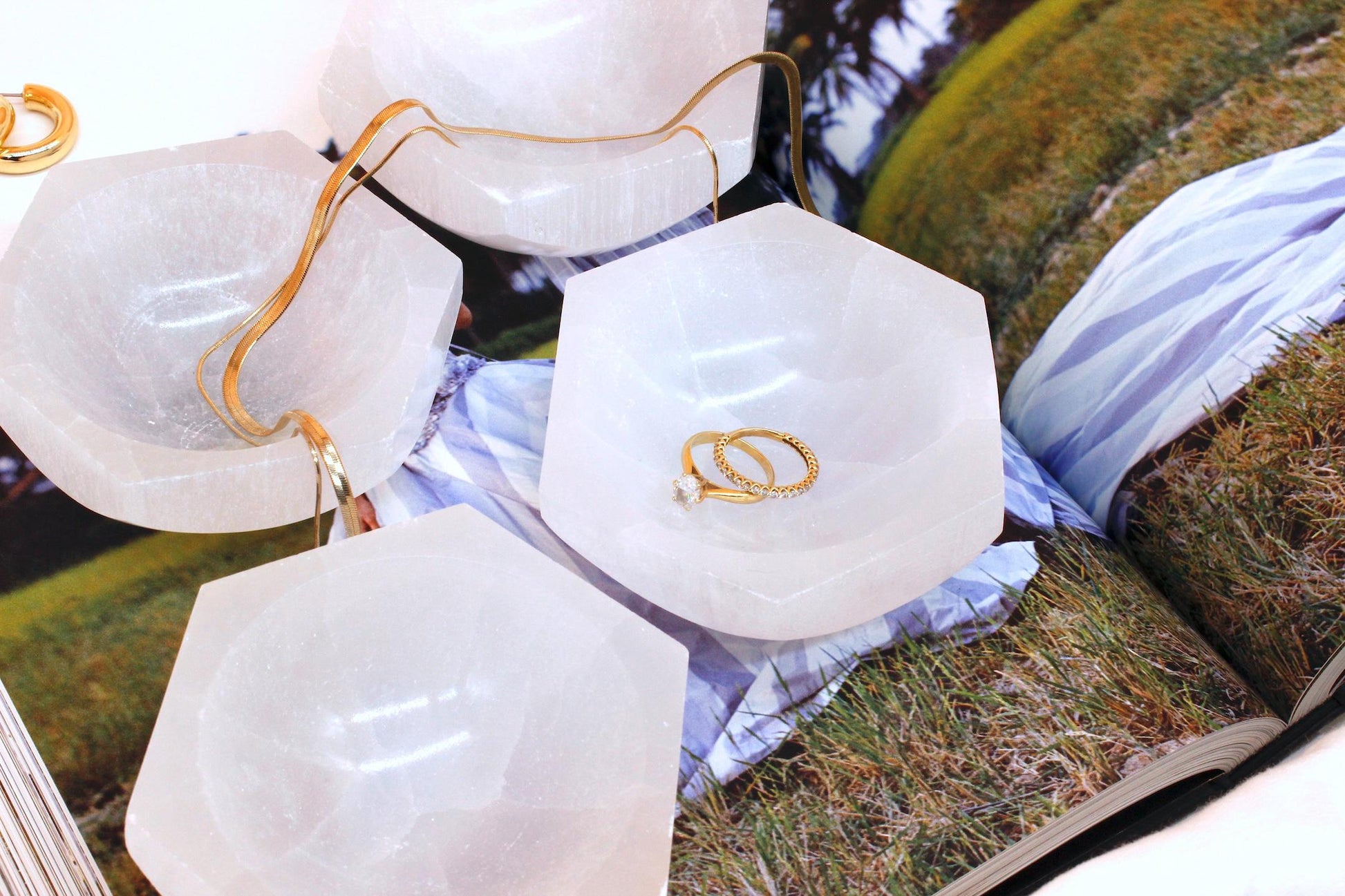 group of white selenite bowls holding gold ring and necklace.