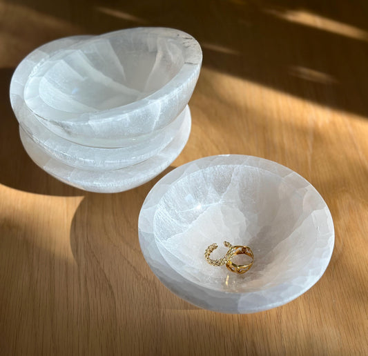 group of white crystal selenite bowls holding gold rings.