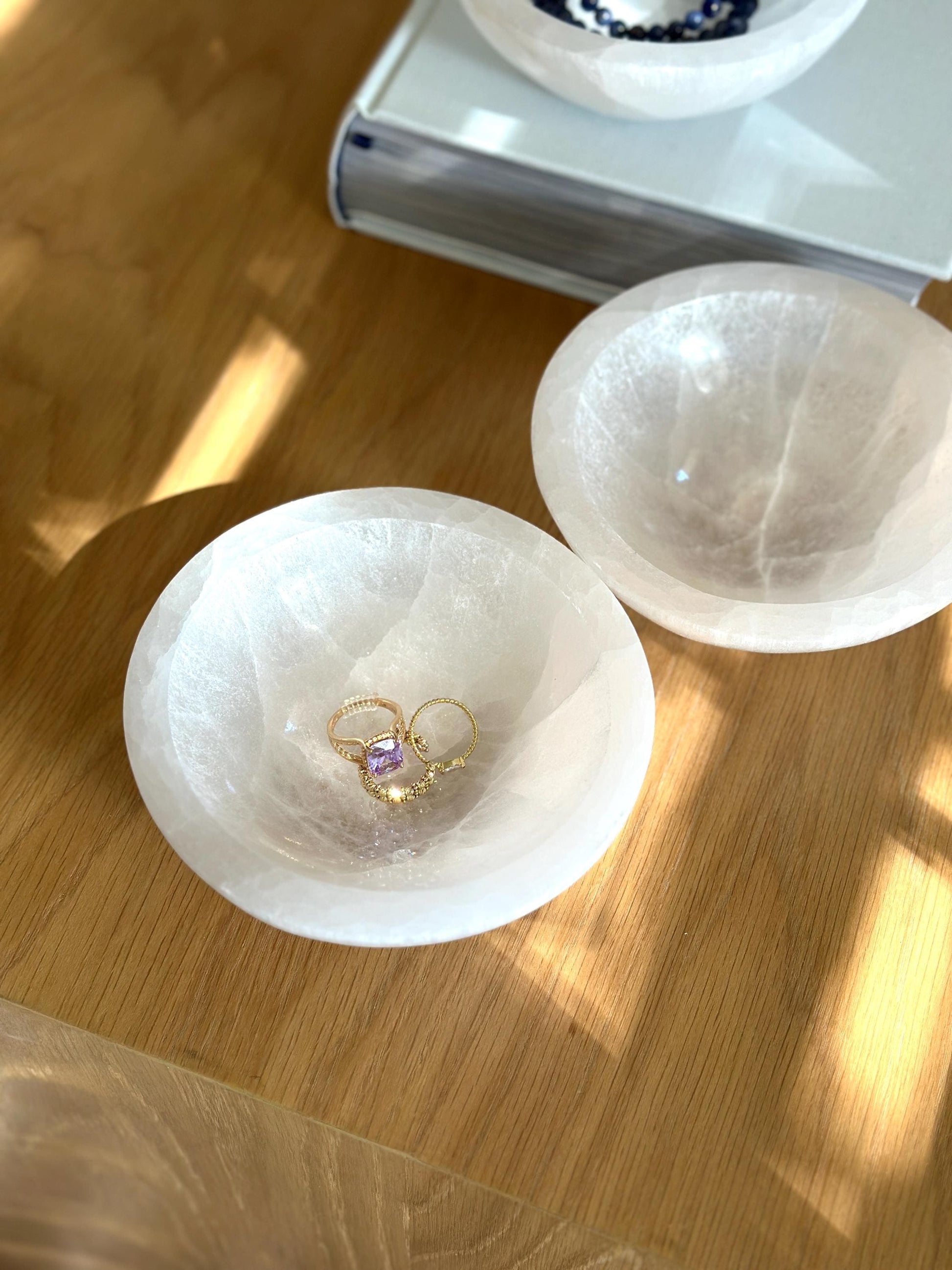 two white catchall bowls holding gold rings.