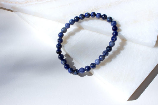 sodalite beaded bracelet laying on white tiles.