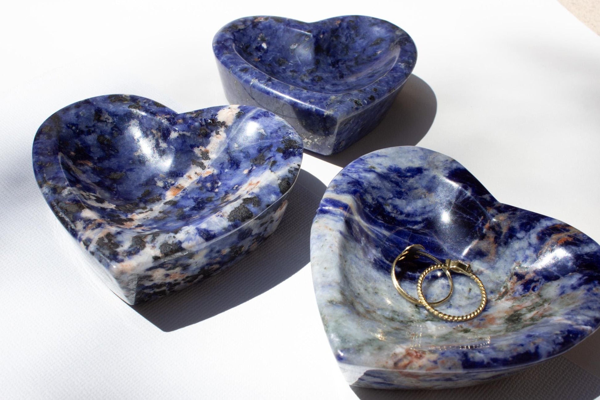 Three small crystal bowls in blue, one is used as a ring holder. All bowls are made of sodalite.