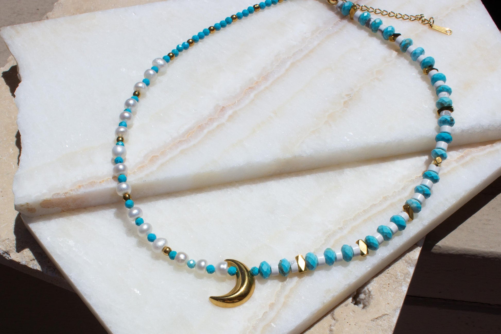 blue and white necklace with a gold moon pendant.