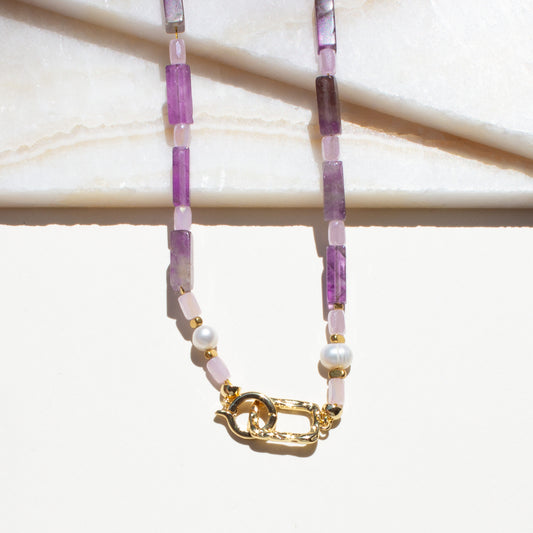 Necklace with purple and pink amethyst beads and a gold clasp on a white background.