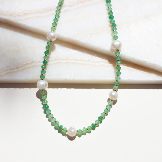 Necklace with green aventurine beads and pearls on a marble surface.