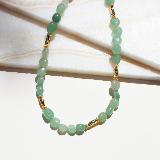 Green beaded aventurine necklace with gold accents on a light background