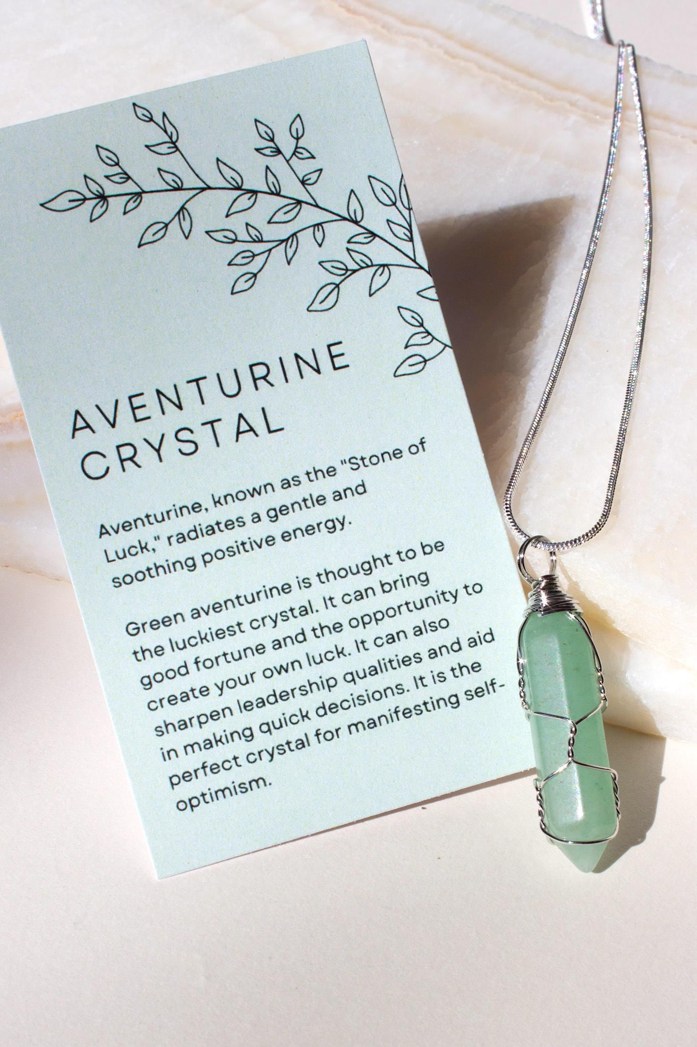 green aventurine necklace next to an aventurine crystal meaning information card. The card is green and explains the enery properties of aventurine. 