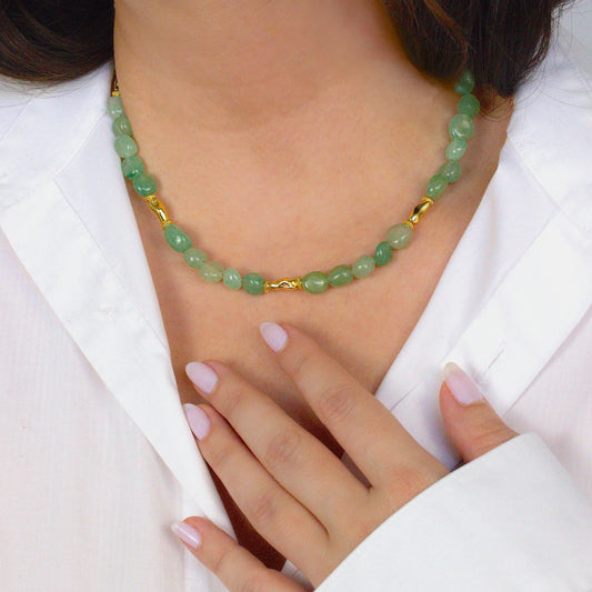 Green beaded necklace with gold accents worn by a person in a white outfit. Green aventurine crystal beads.