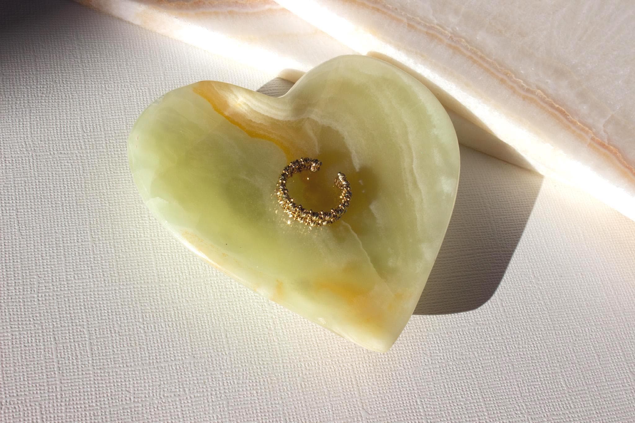 green onyx heart dish holding a gold ring. 