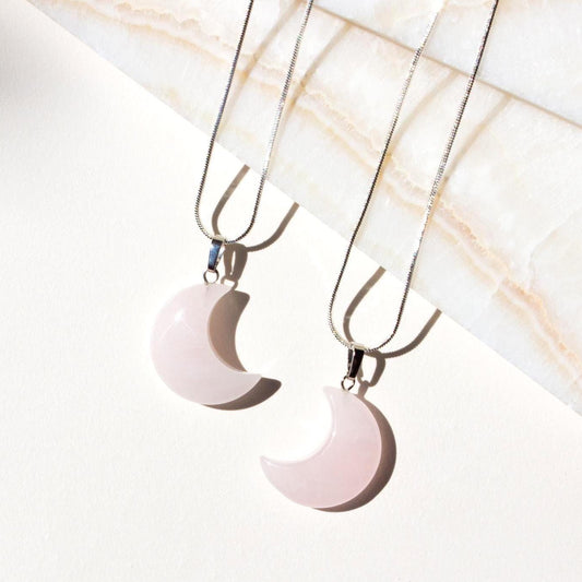 two pink moon pendant necklaces facing eachother. 